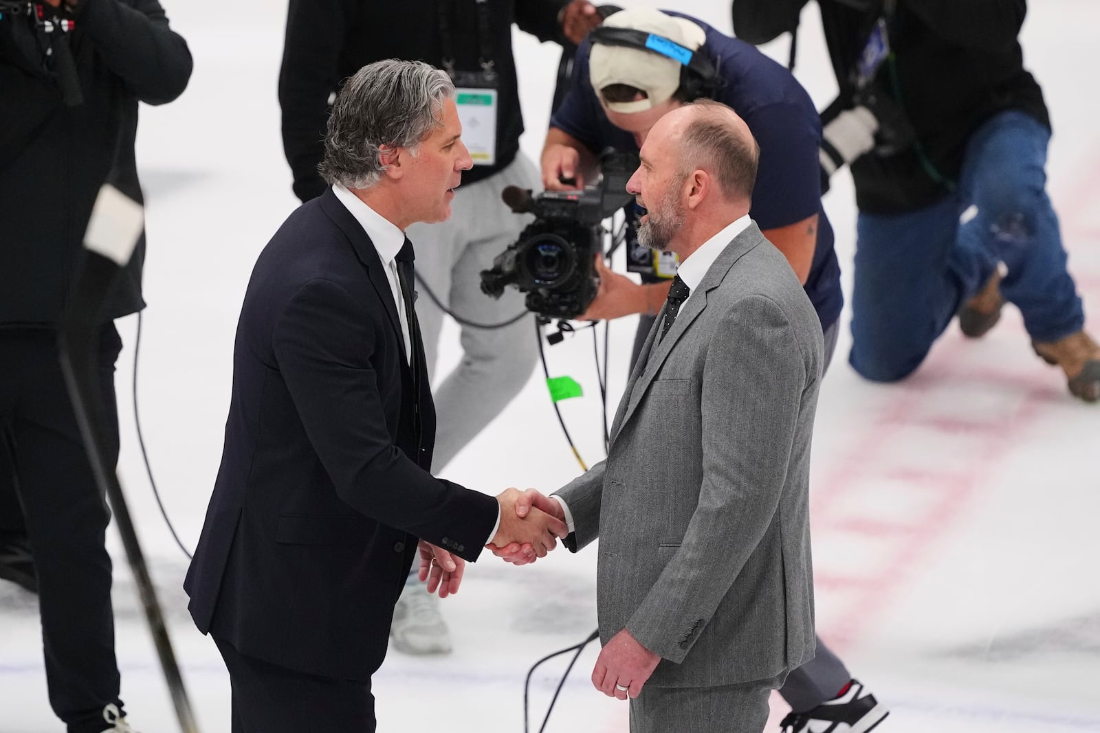 Colorado Avalanche head coach Jared Bednar, left, and Dallas Stars head coach Pete DeBoer, right, greet each other on the ice after their team's Game 7 of a first-round NHL hockey playoff series Saturday, May 3, 2025, in Dallas. (AP Photo/Julio Cortez)