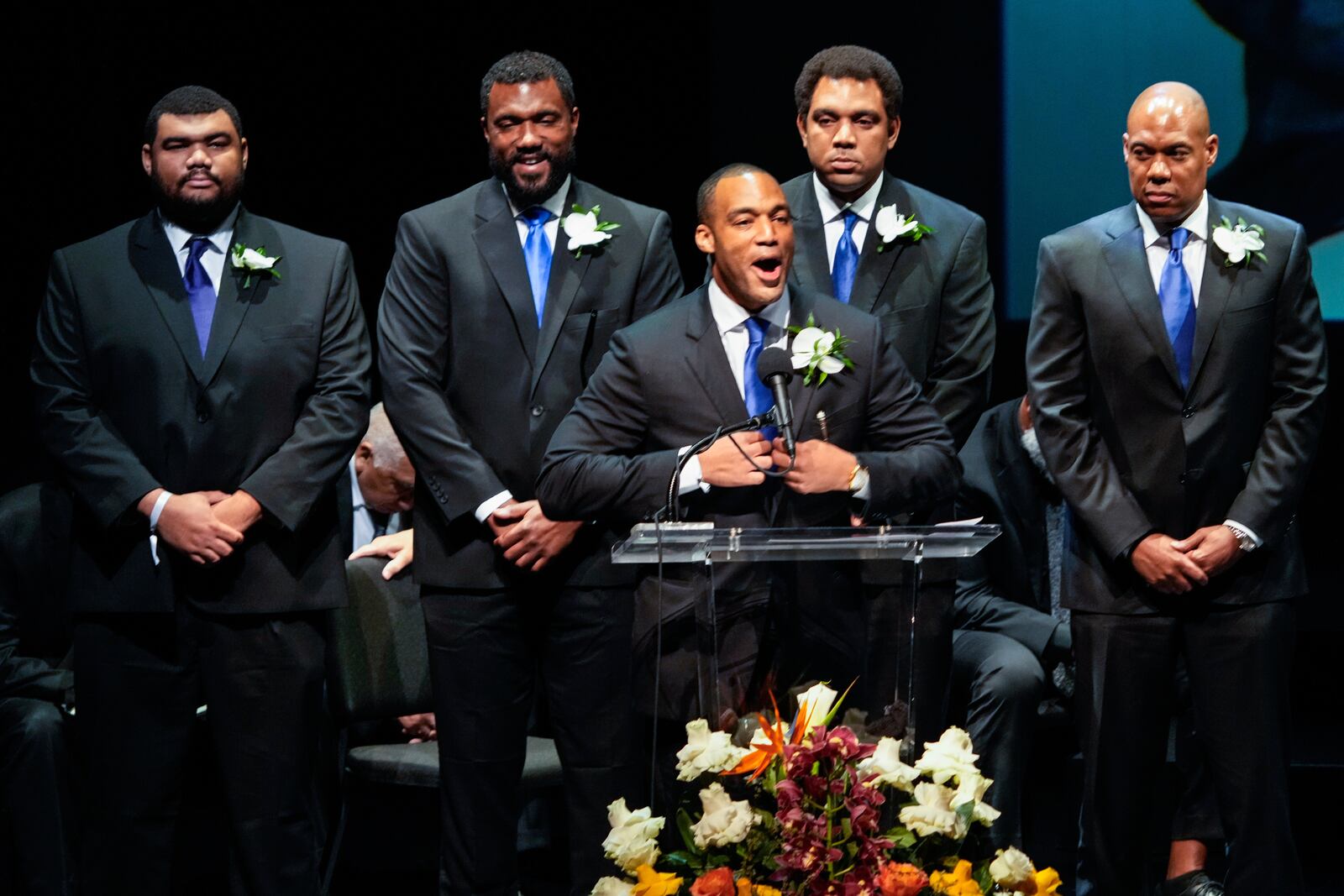 George Foreman IV, center, stands with his brothers as he delivers the eulogy for his father during a memorial service for Olympic and world champion boxer and minister George Foreman at Wortham Theater Center in Houston, Monday, April 14, 2025. (Brett Coomer/Houston Chronicle via AP)