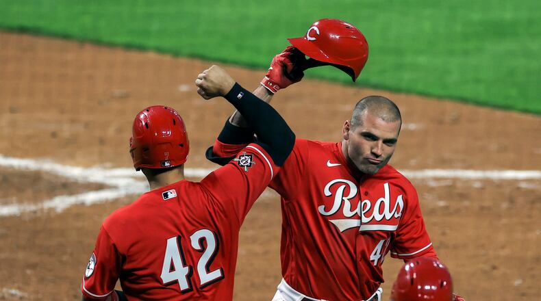 Cincinnati Reds' Eugenio Suarez, left, celebrates the two-run home run by Joey Votto, right, during the third inning of a baseball game against the Cleveland Indians in Cincinnati, Friday, April 16, 2021. (AP Photo/Aaron Doster)