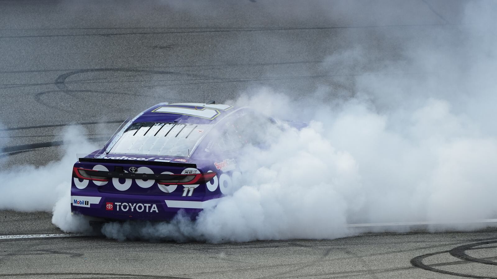 Denny Hamlin celebrates his victory with a burn out after a NASCAR Cup Series auto race at Michigan International Speedway in Brooklyn, Mich., Sunday, June 8, 2025. (AP Photo/Paul Sancya)