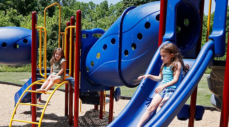 Adrian Massie and her sister, Arrionna, play on the new playground at New Reid Park Thursday. BILL LACKEY/STAFF