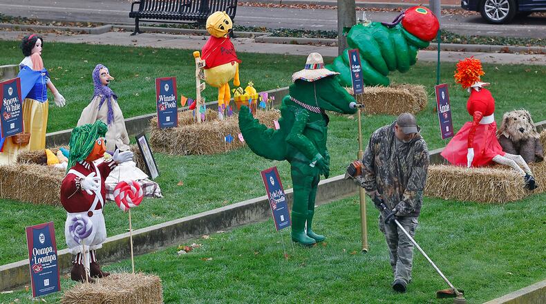 A worker from the National Trail Parks and Recreation District trims the grass around the Project Scare-A-Crow display at National Road Commons Park Monday, Oct. 16, 2023. BILL LACKEY/STAFF