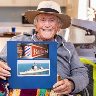 Paul Hughes poses with pictures on Thursday, Nov. 6 at Community Living Center on the VA campus in Dayton. Hughes served in the Navy for about 20 years and worked primarily as a barber while deployed in a destroyer. After retiring from the Navy, he worked as a barber in Dayton. BRYANT BILLING/STAFF