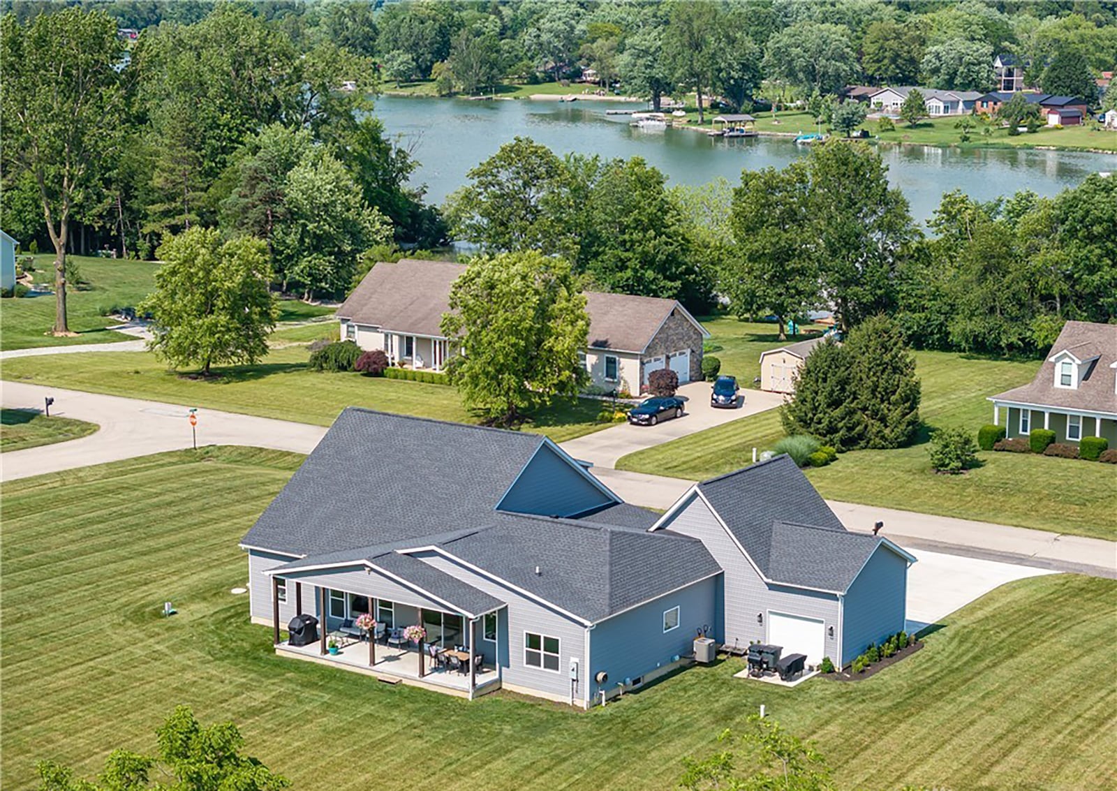 The rear of the home features a covered concrete patio and a backyard lined with trees.