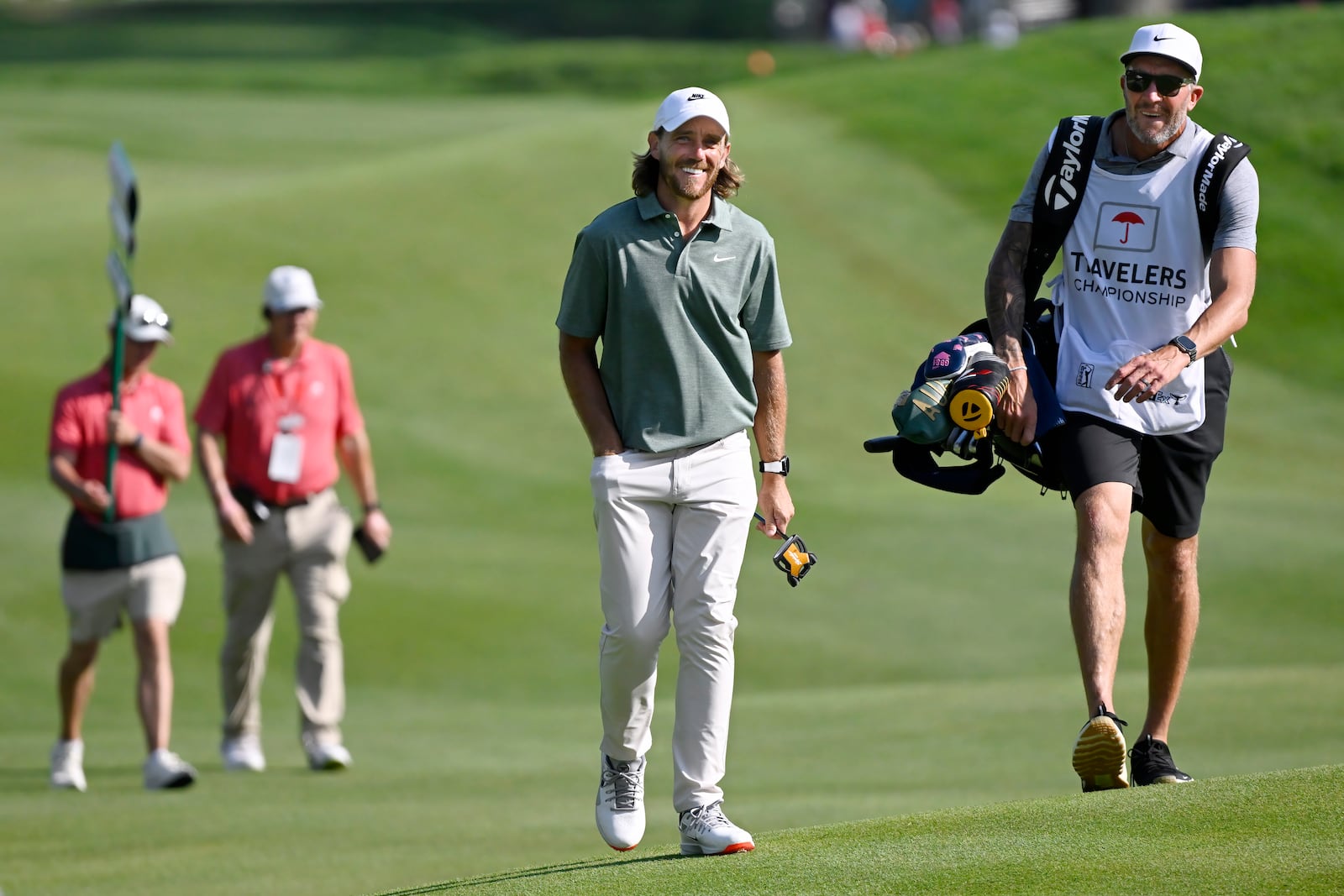 Tommy Fleetwood, center, of England, smiles as he approaches the 18th green during the second round of the Travelers Championship golf tournament at TPC River Highlands, Friday, June 20, 2025, in Cromwell, Conn. (AP Photo/Jessica Hill)