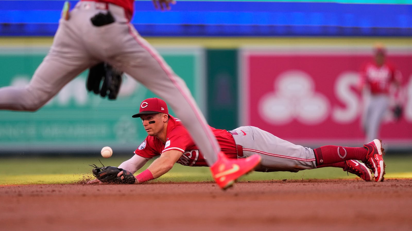 Cincinnati Reds second baseman Matt McLain, right, dives for a ball hit for a single by Jo Adell as shortstop Elly De La Cruz runs by during the first inning of a baseball game Tuesday, Aug. 19, 2025, in Anaheim, Calif. (AP Photo/Mark J. Terrill)