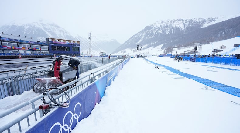 A worker blows snow off a path at the 2026 Winter Olympics, in Livigno, Italy, Wednesday, Feb. 4, 2026. (AP Photo/Gregory Bull)