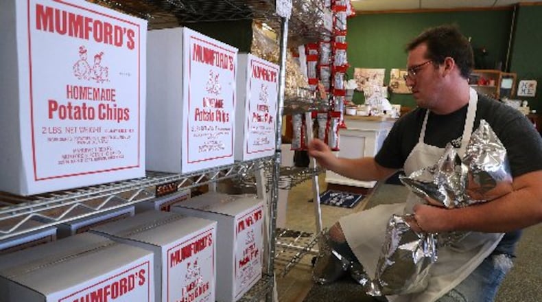 Cody Pack, an employee of Mumford’s Potato Chips, stacks bags of the chips on a shelf. Bill Lackey/Staff
