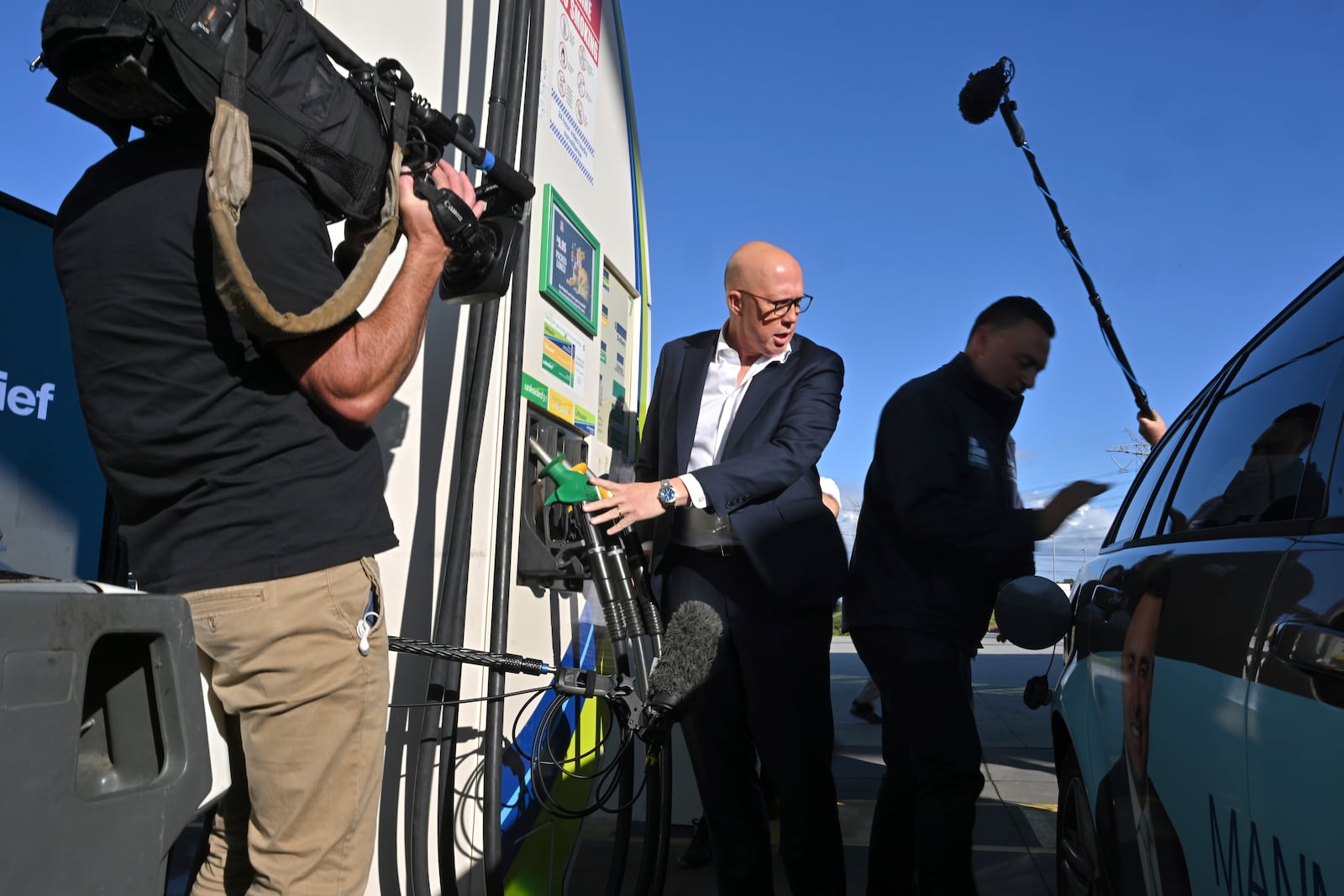 Leader of the Australian opposition Liberal party Peter Dutton, center, assists fueling a car in Melbourne on Wednesday, April 30, 2025. (Mick Tsikas/AAP Image via AP)