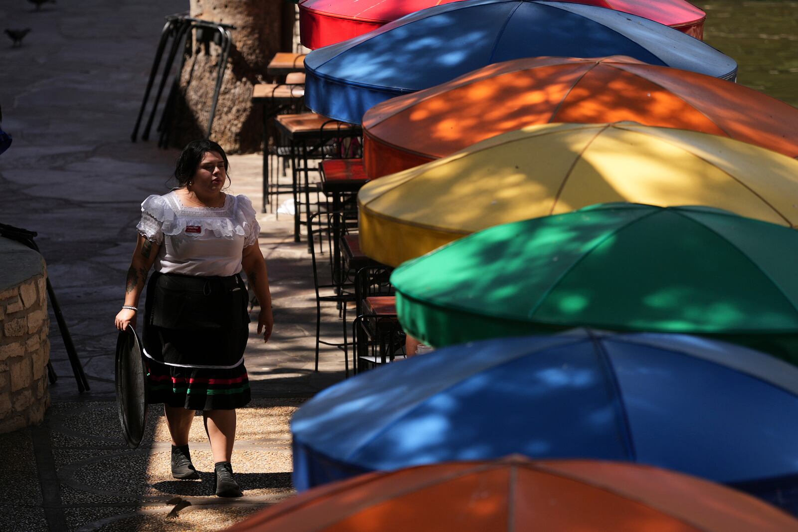 A waitress tends to outdoor patrons as temperatures top the triple-digit mark, Tuesday, May 13, 2025, in San Antonio. (AP Photo/Eric Gay)
