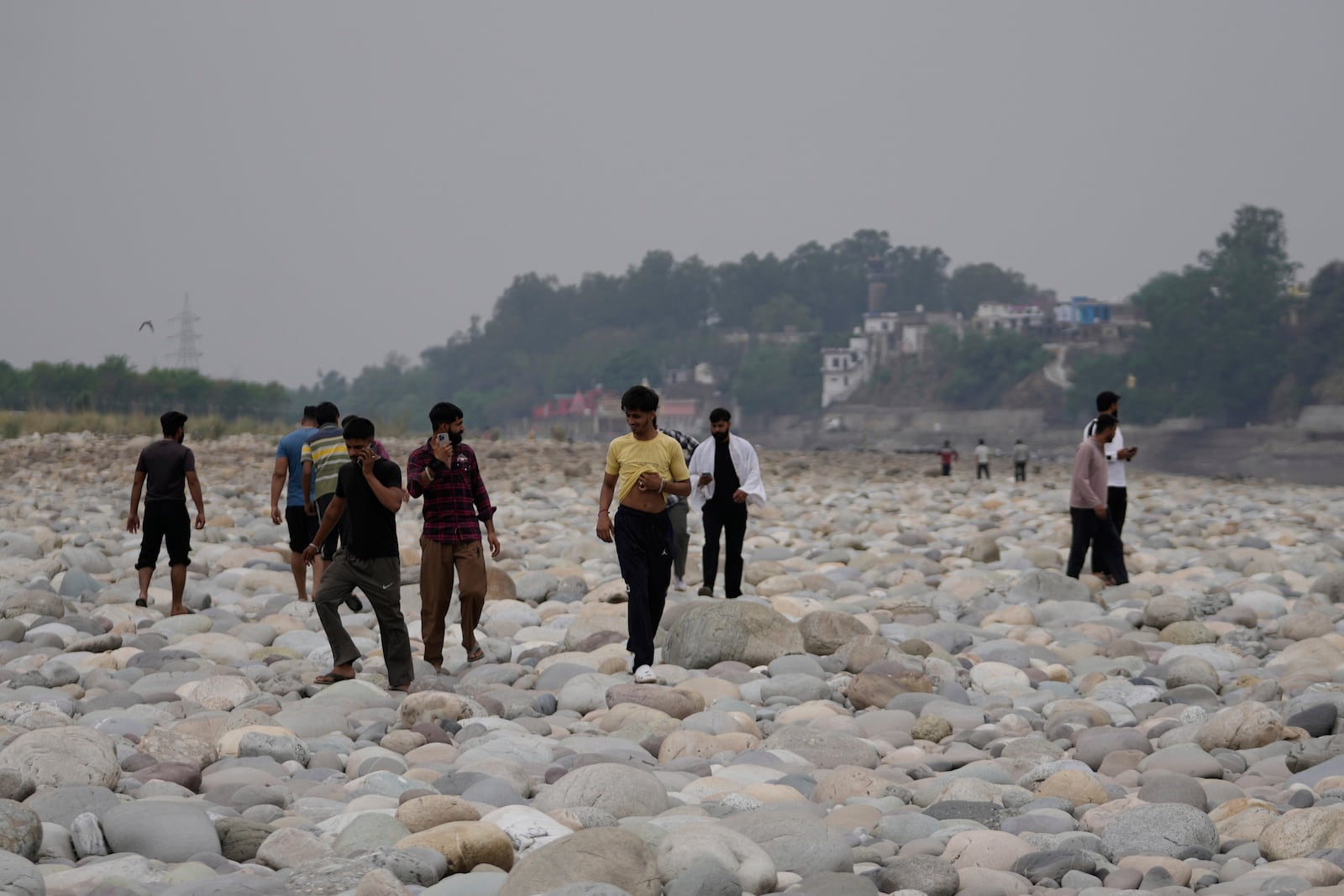 People cross the Chenab River after the flow of water was halted from a dam, at Akhnoor, on the outskirts of Jammu, India, Monday, May 5, 2025. (AP Photo/Channi Anand)