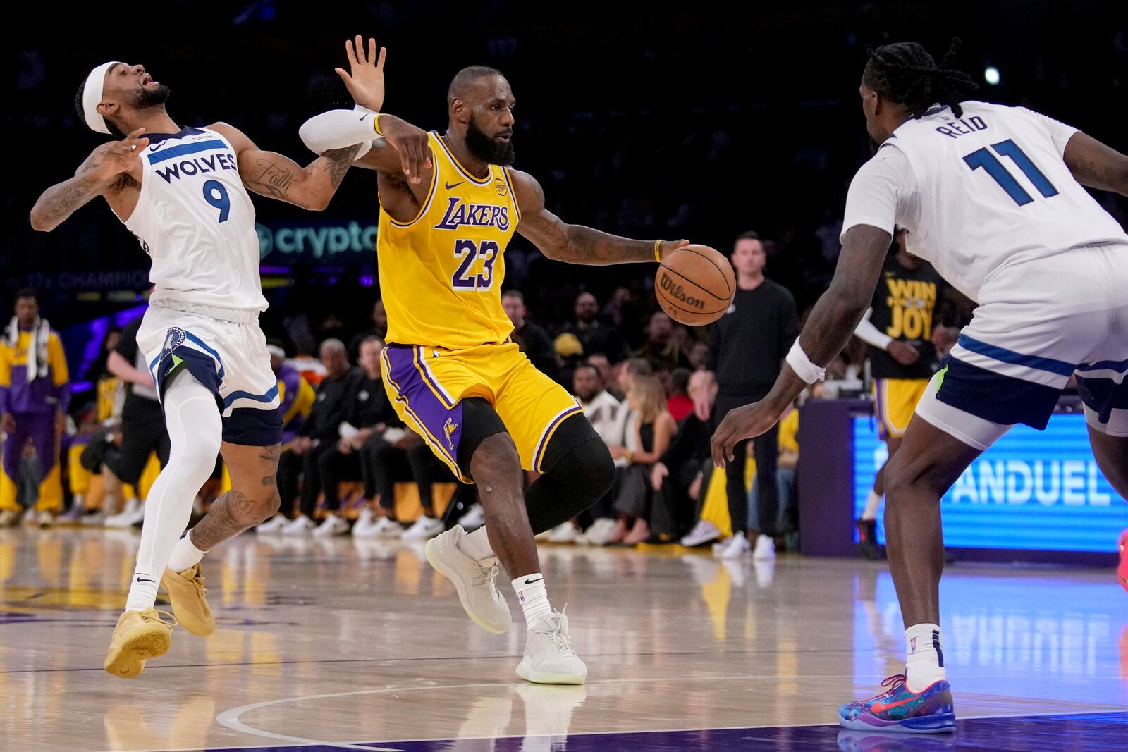 Los Angeles Lakers forward LeBron James (23) dribbles against Minnesota Timberwolves guard Nickeil Alexander-Walker (9) and center Naz Reid (11) during the first half of Game 2 of an NBA first-round playoff series in Los Angeles, Tuesday, April 22, 2025. (AP Photo/Eric Thayer)