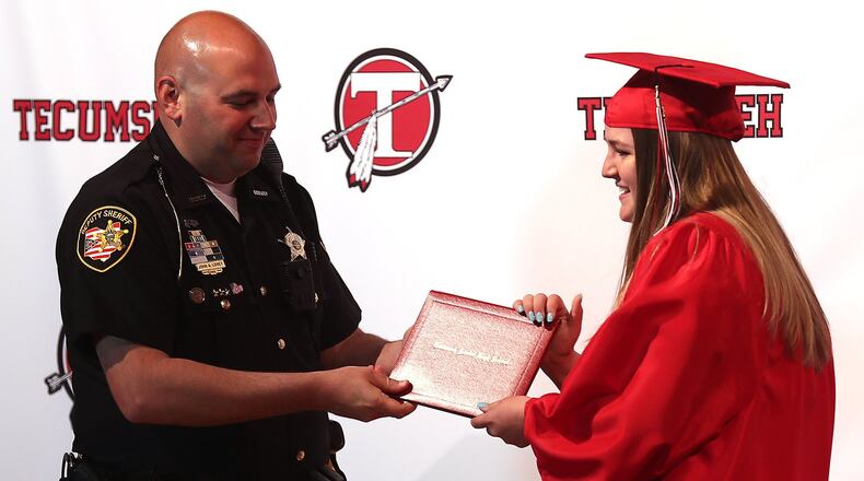 Deputy John Loney, school resource officer at Tecumseh Local Schools, presents Ellie Gehret with her diploma Monday during her individual graduation ceremony. BILL LACKEY/STAFF