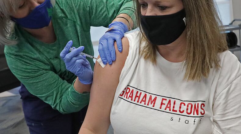 Mindy Bechtel, a guidance counselor at Graham High School, gets the COVID vaccine from Holly McGowen at the Champaign County Health District on Jan. 29. BILL LACKEY/STAFF