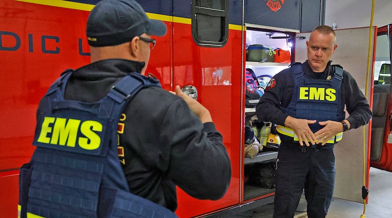City of Springfield firefighters Corey Miller, left, and Jim Frantz put on the new bullet proof vests that the department just received due to the increasing threat on first responders. BILL LACKEY/STAFF