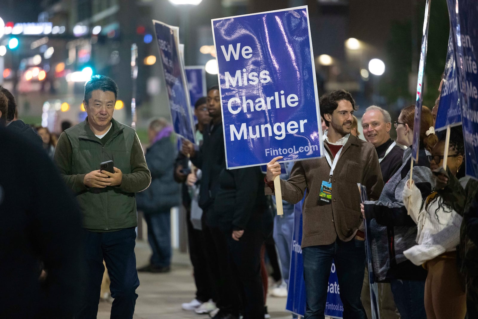 Nicolas Bustamante of San Francisco, CEO of fintool.com, holds a sign reading, "We miss Charlie Munger," alongside several others as shareholders arrive outside CHI Health Center Omaha for the Berkshire Hathaway annual meeting Saturday, May 3, 2025, in Omaha, Neb. (AP Photo/Rebecca S. Gratz)