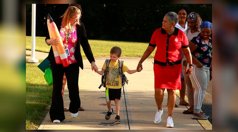 A student holds hands with the staff at Fulton Elementary as they walk into school for the first day Wednesday, August 14, 2024. BILL LACKEY/STAFF