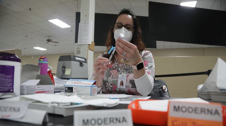 Coronavirus cases have jumped to nearly 200 in Clark and Champaign County schools. Here, Kristen Earley gets a COVID vaccine shot ready at the Clark County Combined Health District's vaccine center earlier this year. BILL LACKEY/STAFF