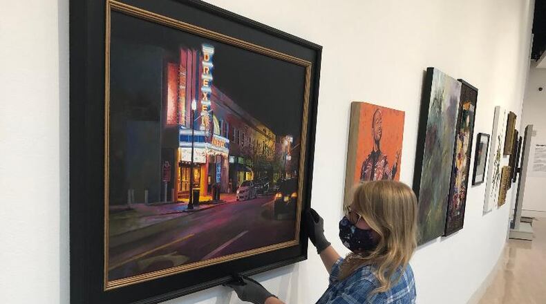 The Springfield Museum of Art and two other local arts institutions are closing temporarily due to the pandemic. Elizabeth Wetterstroem adjusts artwork at the museum in August. BRETT TURNER/CONTRIBUTED