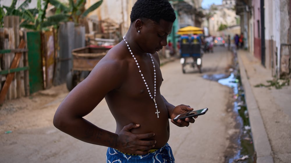 A man wearing a rosary looks at his phone during a blackout in Havana, Cuba, Thursday, March 5, 2026. (AP Photo/Ramon Espinosa)