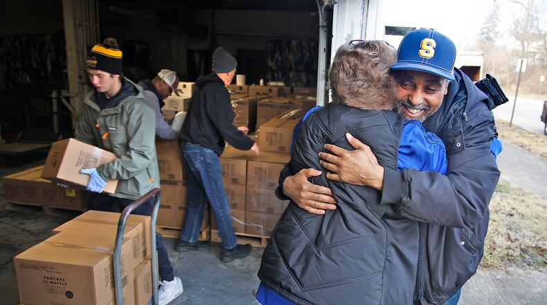 James Wallace, from Sheltered Inc., hugs Casey Rollins, the St. Vincent de Paul executive director, as others load a cart with boxes of food Wednesday, Jan. 3, 2024 at the St. Vincent warehouse. Food pantries from around the area are getting some extra help after St. Vincent received a 40,000-pound food donation from the Church of Jesus Christ of Latter-day Saints. BILL LACKEY/STAFF