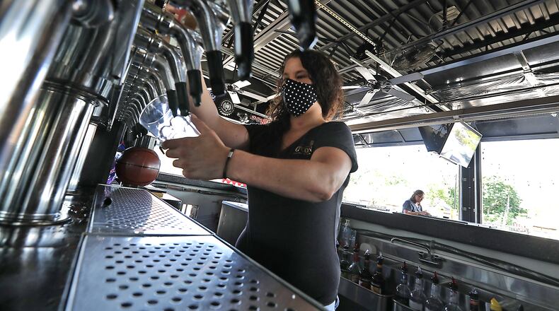 Nikki Callicoat pours a draft beer behind the bar at O'Conner's Irish Pub Friday. BILL LACKEY/STAFF