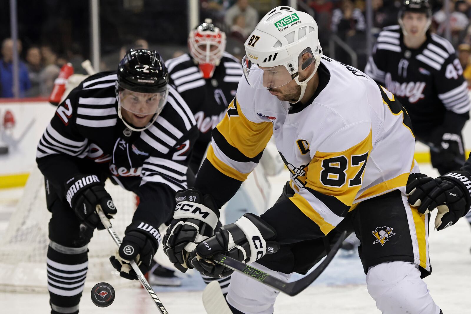 Pittsburgh Penguins center Sidney Crosby (87) battles for the puck with New Jersey Devils defenseman Brian Dumoulin in the third period of an NHL hockey game Friday, April 11, 2025, in Newark, N.J. (AP Photo/Adam Hunger)