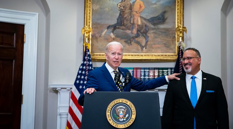**EMBARGO: No electronic distribution, Web posting or street sales before 3:01 a.m. ET Tuesday, Aug. 30, 2022. No exceptions for any reasons. EMBARGO set by source.** President Joe Biden recognizes Education Secretary Miguel Cardona while speaking about a student loan debt relief plan in the Roosevelt Room of the White House in Washington on Aug. 24, 2022. Liberals and more moderate Democrats are arguing over the impact on inflation, the federal budget deficit and high earners. (Al Drago/The New York Times)