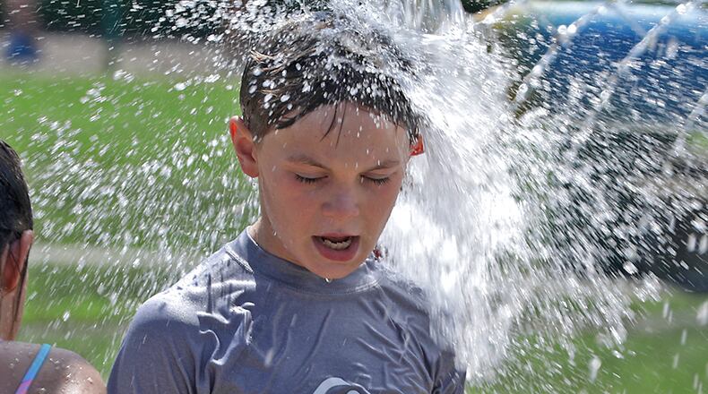 A bucket of water pours over Stone Lane's head as he plays on the Snyder Park Sprayground Wednesday, June 15, 2022. The Sprayground was opened for the first time this season on Wednesday. It had been out of commission since last year but National Trail Parks and Recreation got it working just in time for one of the hottest days of the year. BILL LACKEY/STAFF
