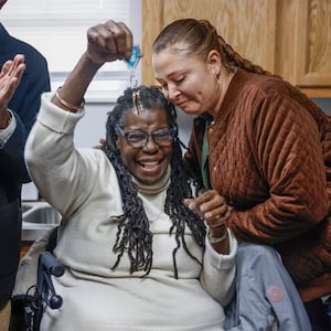 Gwendolyn Iheme, center, celebrates by holding a key to her new house that was given to her by Springfield Restore manager Rathena Austin, right, during a home dedication hosted by the Habitat for Humanity of Greater Dayton on Friday, Dec. 12, 2025, in Springfield. The ceremony was for Iheme, who will live in the house with her 8-year-old granddaughter Rileyanna Foster. JOSEPH COOKE/STAFF