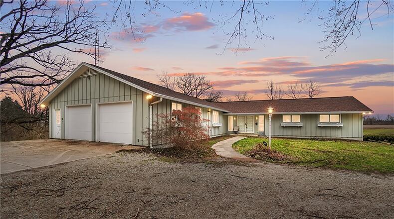 The custom ranch has a unique floorplan and a winding gravel driveway that connects the road to the property and there is a gate at the end of the drive.
