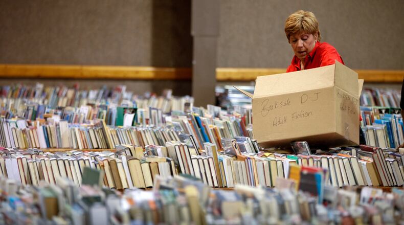 Casi Lombardo, a volunteer from Lexis Nexis, stacks books on tables in preparation for the Friends of the Dayton Metro Library Booksale at Hara Arena.