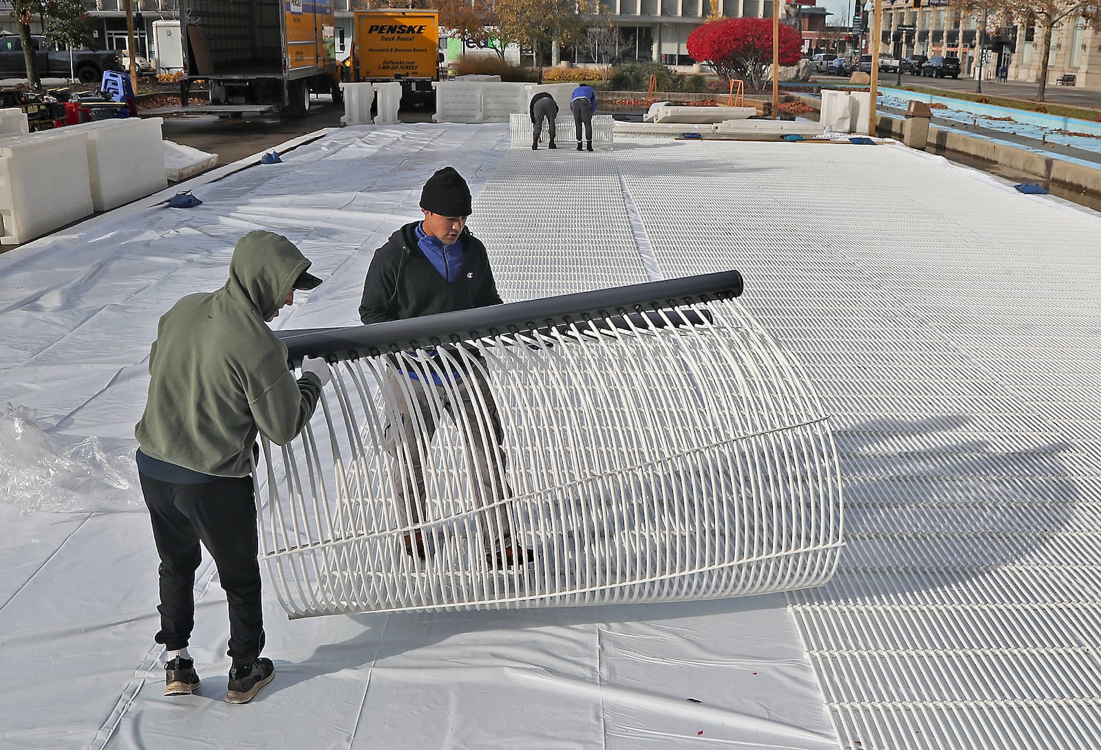 A crew from All Year Sports Galaxy works to build a temporary ice skating rink on the Springfield City Hall Plaza Thursday. The workers unrolled sheets of plastic tubing that will cool the water from underneath. The Greater Springfield Partnership will open the skating rink on Nov. 26 at 5 p.m. prior to the city’s Grand Illumination event. The ice rink, which is 40 feet by 80 feet, will be open on Thursdays through Sundays until Jan. 2. The cost to use the ice rink will be $5, including skate rental.. BILL LACKEY/STAFF