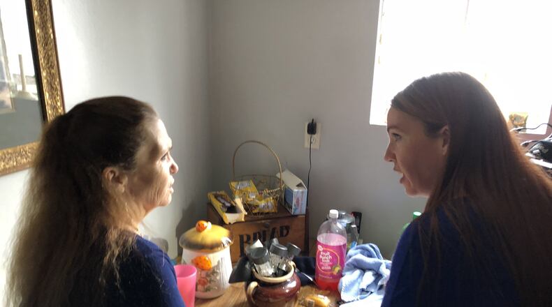 Sue Bailey at left looks over a photo album with her eldest daughter, Jenna Behrmann. They were recently reunited after Bailey put her daughter up for adoption more than 30 years ago. STAFF/LAWRENCE BUDD