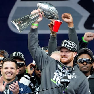 Seattle Seahawks quarterback Sam Darnold holds the Lombardi Trophy as head coach Mike MacDonald celebrates at left during the team's NFL football Super Bowl 60 celebration at Lumen Field, Wednesday, Feb. 11, 2026, in Seattle. (AP Photo/Stephen Brashear)