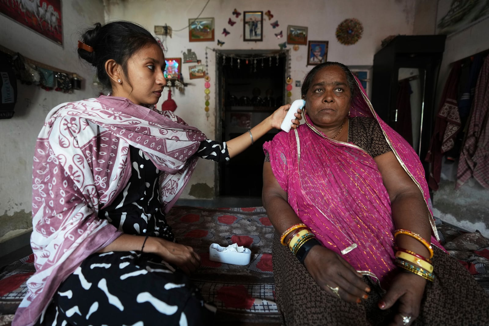 Field data collector Manisha Parmar, left, checks the temperature of Shantaben Vanzara in Ahmedabad, India, Wednesday, April 2, 2025. (AP Photo/Ajit Solanki)