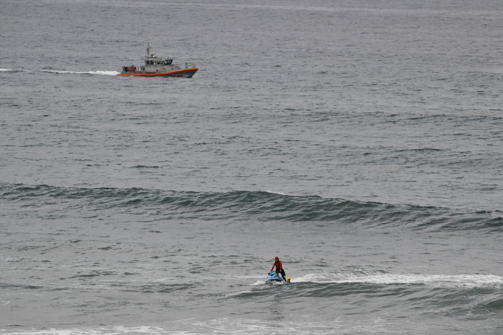 A U.S Coast Guard boat and lifeguards look for survivors after a boat capsized in the surf Friday, May. 5, 2025, in at Torrey Pines State beach in San Diego, Calif. (AP Photo/Denis Poroy)