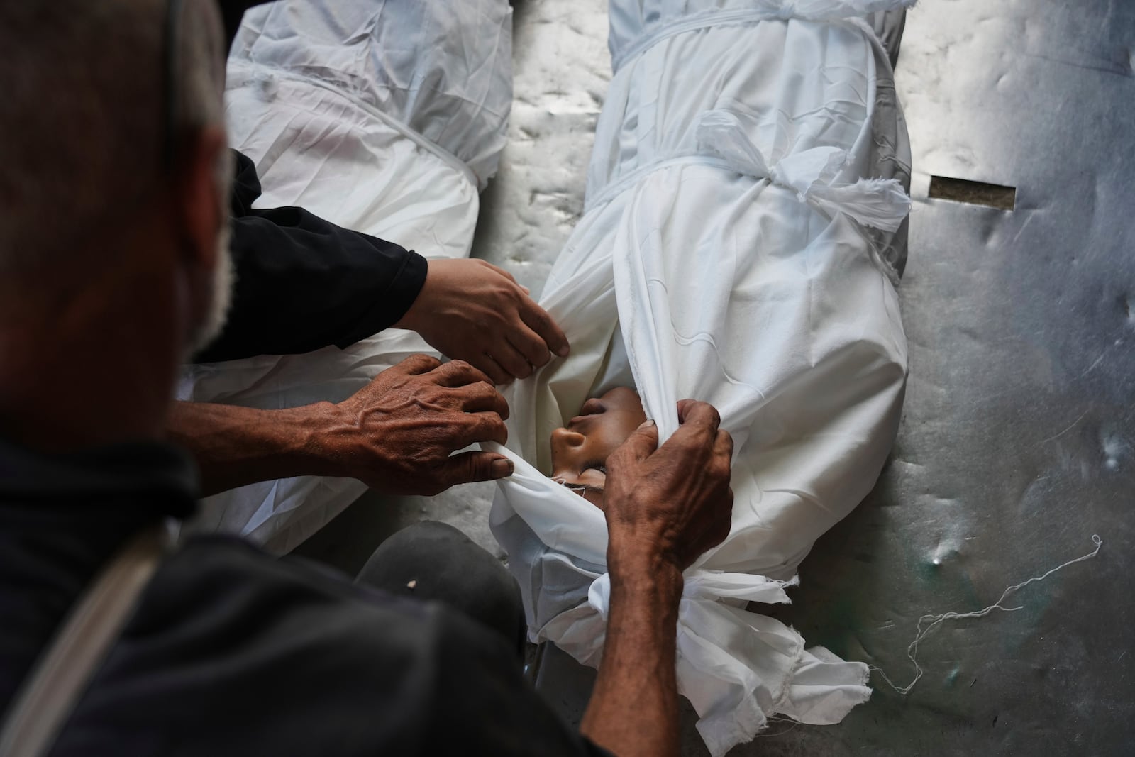 Relatives look at the body of Palestinian child Abdullah al-Rantisi, 11, killed by an Israeli military bombardment, in Deir al-Balah, central Gaza Strip, Monday, July 21, 2025. (AP Photo/Abdel Kareem Hana)