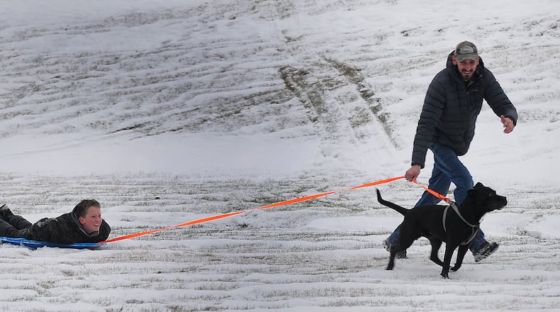 Gabriel Spitler, 11, gets a sled ride at Osborne Park in Fairborn from his father Jordan and his dog Shadow, Tuesday Dec. 28, 2022. MARSHALL GORBY\STAFF