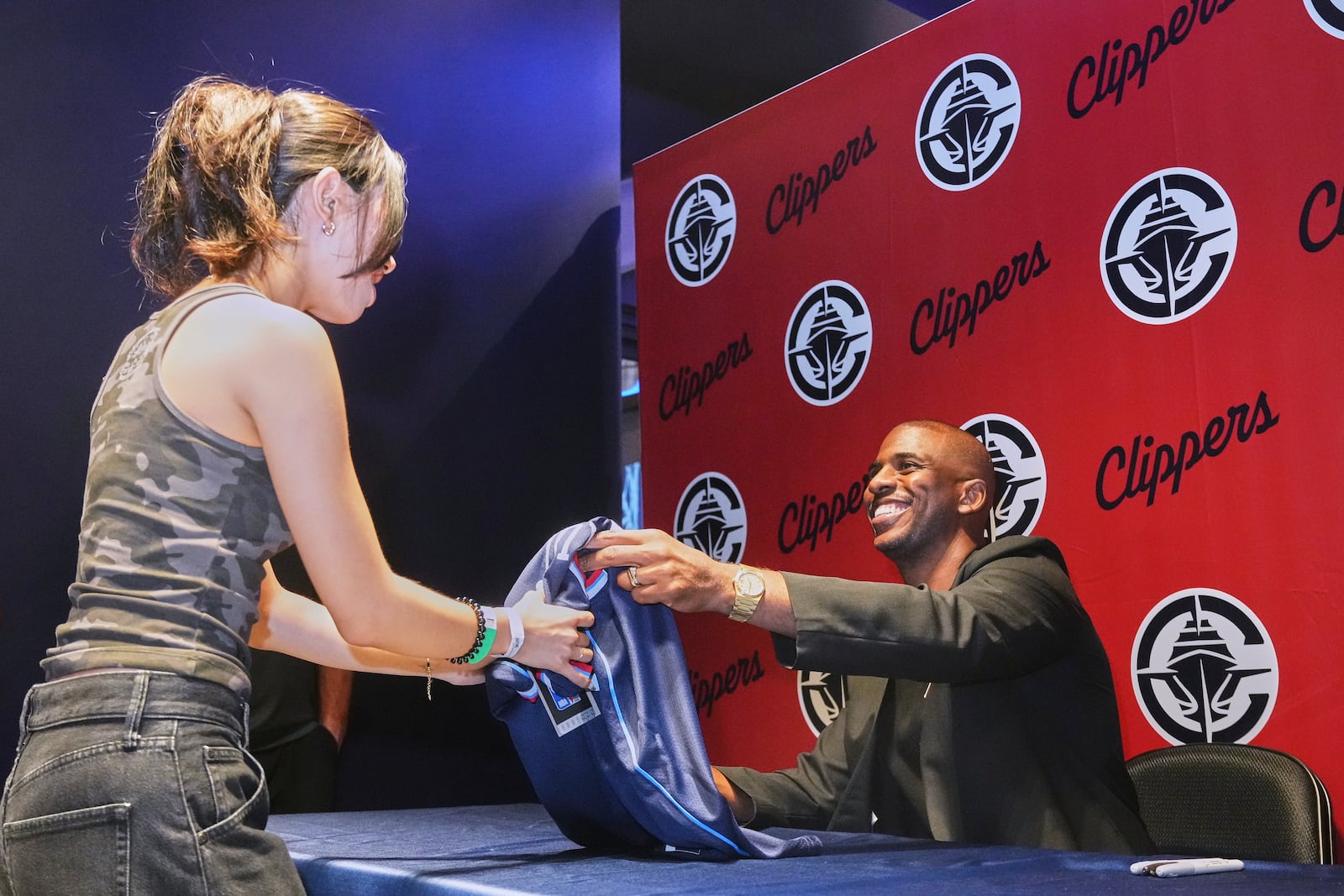 Chris Paul , left, signs Los Angeles Clippers jerseys after being introduced as the newest member of the team during an NBA basketball news conference in Inglewood, Calif., Monday, July 28, 2025. (AP Photo/Damian Dovarganes)