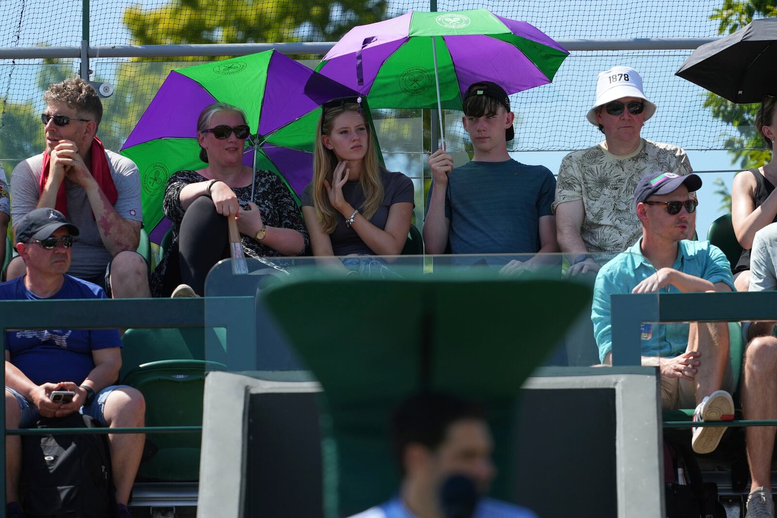 Spectators shelter from the sun on day one at the Wimbledon Tennis Championships in London, Monday, June 30, 2025. (AP Photo/Joanna Chan)