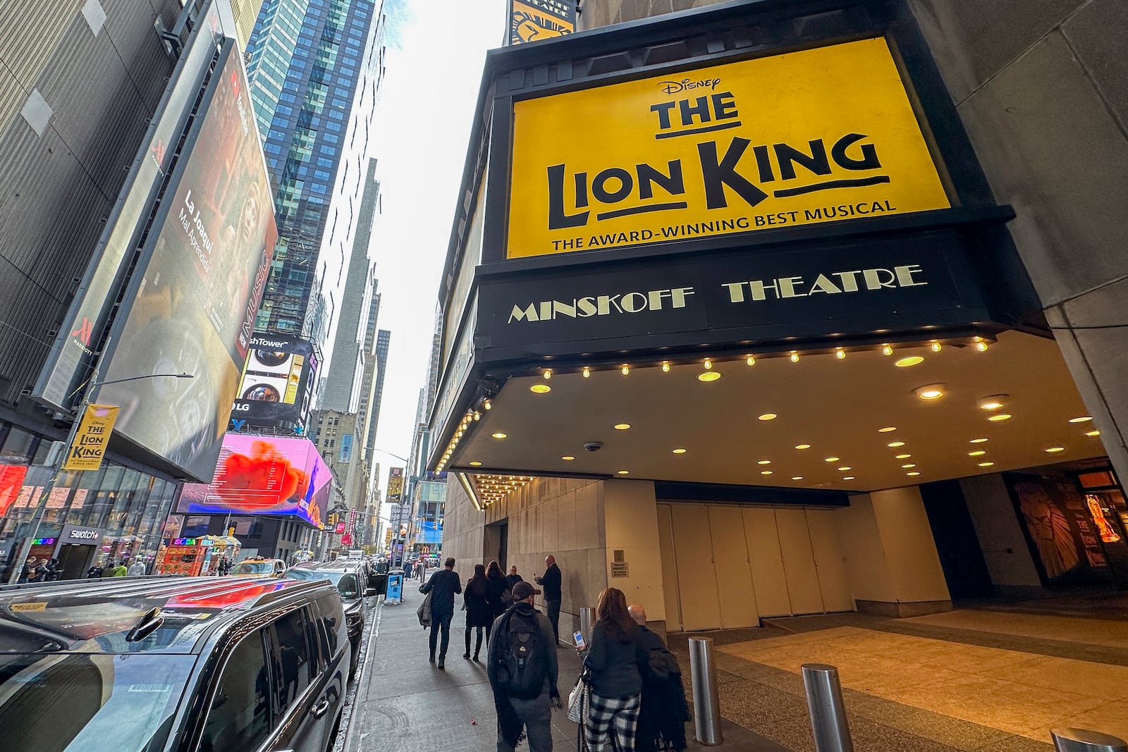FILE — People walk in front of the Minskoff Theatre where "The Lion King" plays on Broadway in New York, Nov. 16, 2023. (AP Photo/Ted Shaffrey, File)