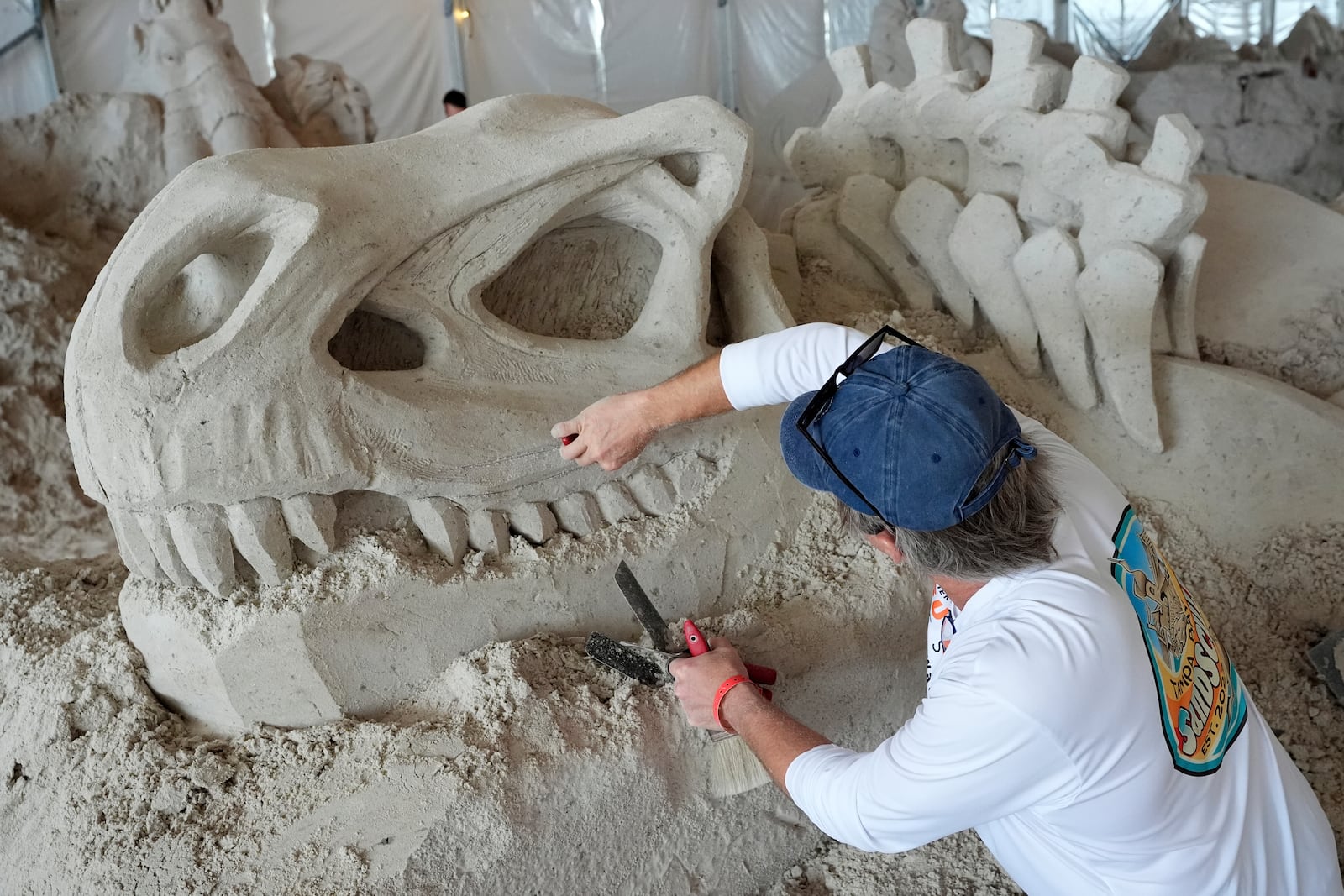 Dan Belcher, of St. Louis, Mo., works on his sand sculpture during preparation for the Pier 60 Sugar Sand Festival's "DinoShores: a Prehistoric Adventure in Sand" Monday, April 7, 2025, in Clearwater Beach, Fla. (AP Photo/Chris O'Meara)
