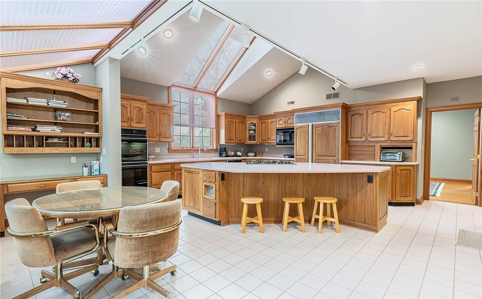 the kitchen has a solarium style breakfast nook with multiple skylights, wood cabinets and high end appliances.