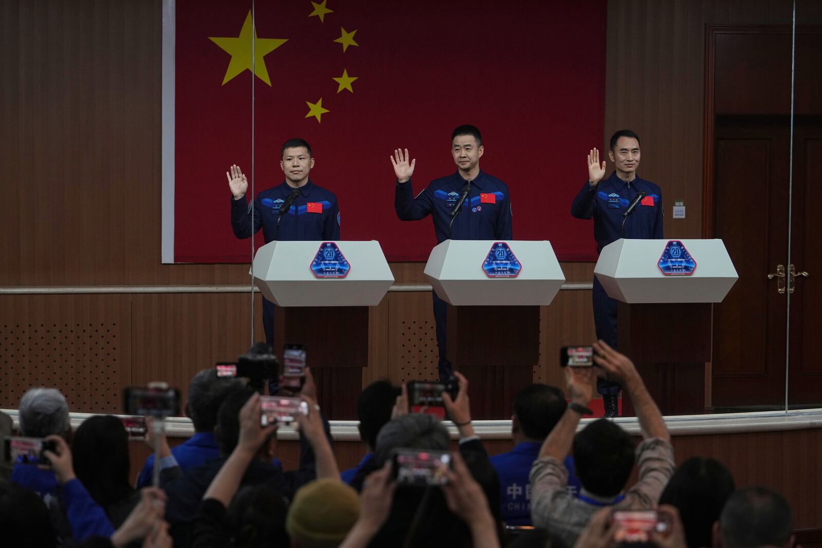 Journalists film Chinese astronauts for the upcoming Shenzhou 20 mission, from left, Wang Jie, captain Chen Dong and Chen Zhongrui wave at the Jiuquan Satellite Launch Center in northwest China, Wednesday, April 23, 2025. (AP Photo/Andy Wong)
