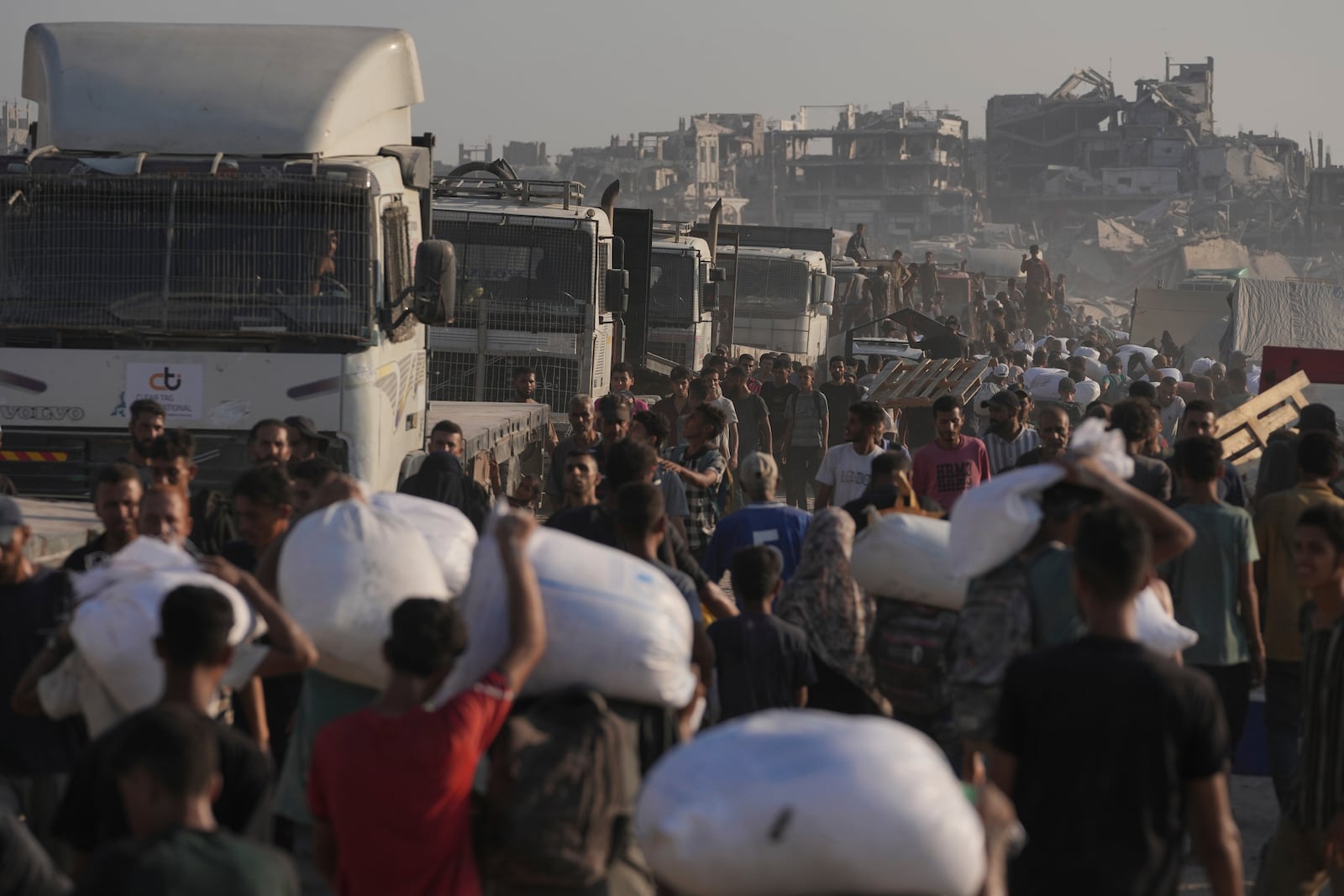Palestinians carry sacks of flour unloaded from a humanitarian aid convoy that reached Gaza City from the northern Gaza Strip, Saturday, July 26, 2025. (AP Photo/Jehad Alshrafi)