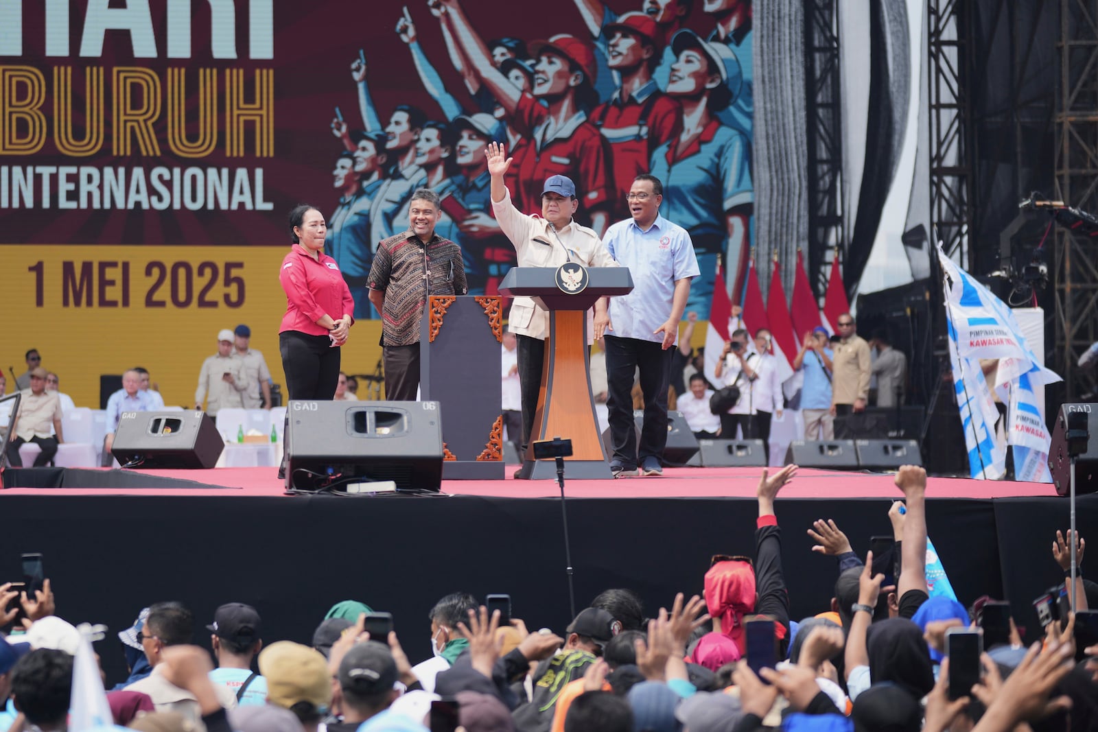 Indonesian President Prabowo Subianto, center, waves at the crowd as labor group leaders, from left, Elly Rosita Silaban, Said Iqbal, and Jumhur Hidayat, right, look on during a May Day rally at the National Monument in Jakarta, Indonesia, Thursday, May 1, 2025. (AP Photo/Tatan Syuflana)