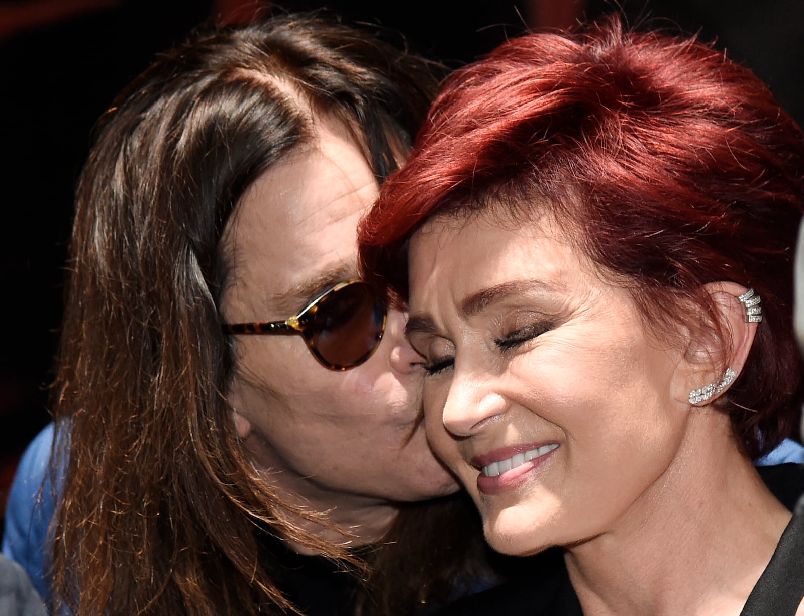 FILE - Ozzy Osbourne kisses his wife Sharon during the "Ozzfest Meets Knotfest" news conference at the Hollywood Palladium, May 12, 2016, in Los Angeles. (Photo by Chris Pizzello/Invision/AP, File)