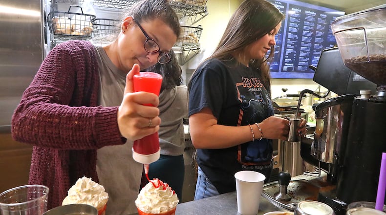 Tawny Longworth, left, and Nikki Hyder make coffee drinks at Penny Lane Art Gallery & Cafe in New Carlisle Monday, Oct. 24, 2022. BILL LACKEY/STAFF