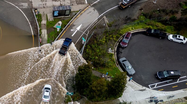 Vehicles drive on a flooded road during a king tide event in Corte Madera, Calif., Saturday, Jan. 3, 2026. (Stephan Lam/San Francisco Chronicle via AP)